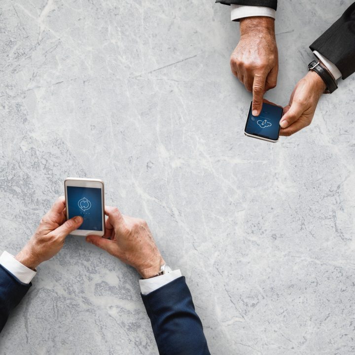 Two sets of hands working on mobile devices